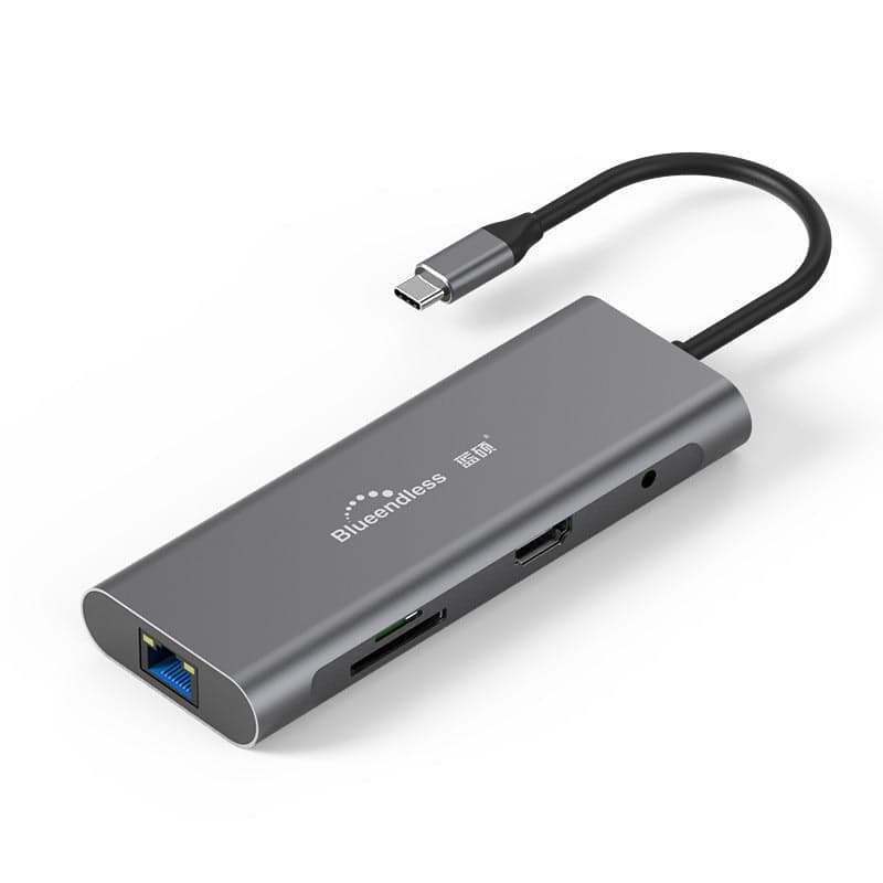 Grey aluminium 9-in-1 USB-C hub shown at an angle, with its RJ45 Ethernet port, 3.5 mm audio jack, HDMI port and card slots visible