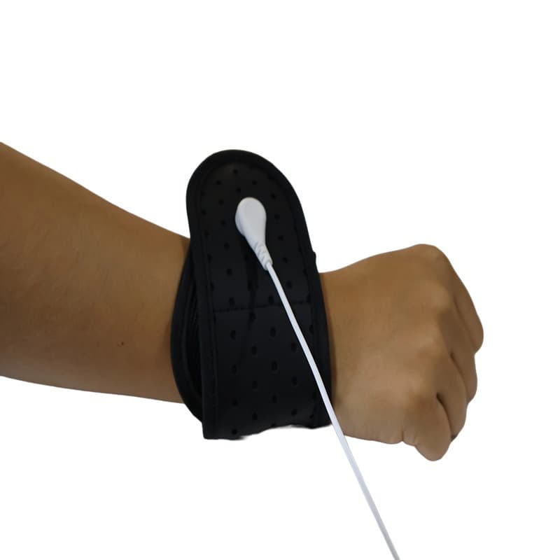 Black fabric anti-static wrist strap worn on a forearm, with a pale grounding lead attached at a stud on the band
